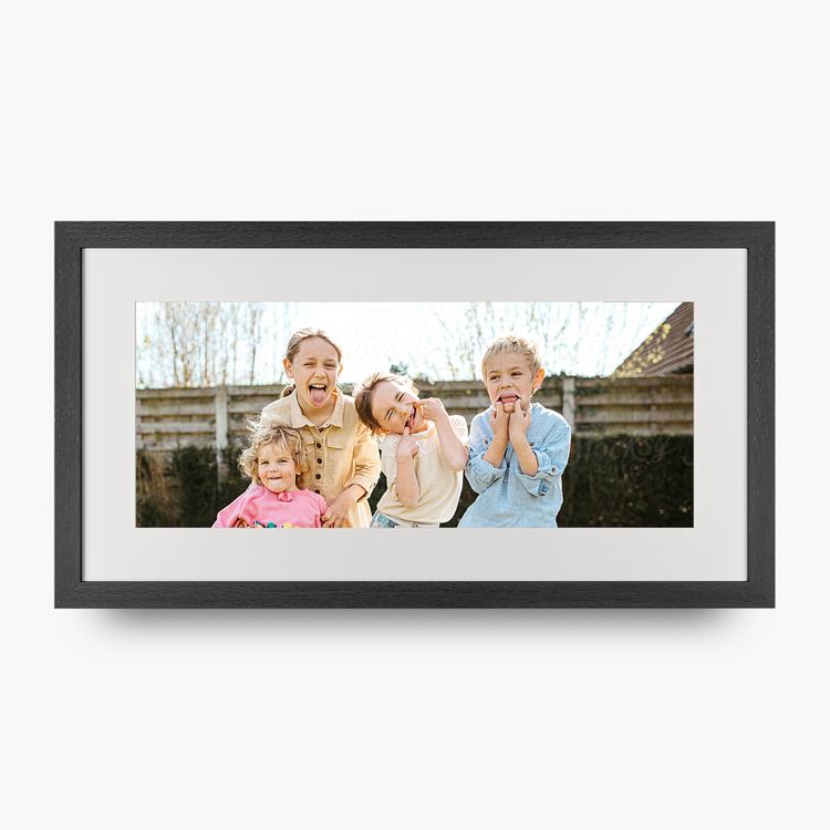 A custom panoramic framed photo print featuring a family of four outdoors, displayed on a clean white background with a subtle drop shadow.